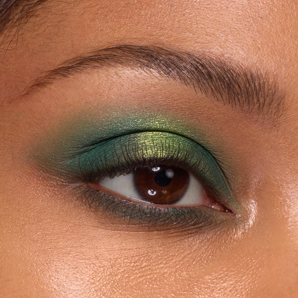 Eyelid wearing Just My Luck shades from the ColourPop Shadow Palette, blending emerald to lime metallic greens across the lid, with soft shimmer, defined lashes, and a groomed brow, illustrating bold pigment and seamless blend.