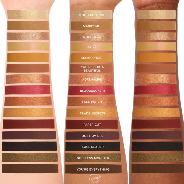 ColourPop New Moon Shadow Palette swatches stripe three skin tones, showing warm golds, coppers, reds, browns, black and olive in matte and shimmer finishes, with shade names like Mood Control, Marry Me, Adrenaline, Bloodsuckers, and You’re Everything.