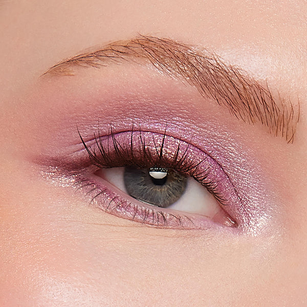 Shimmery pink-lilac eyeshadow sweeps across the upper lid and inner corner on a close-up gray eye, catching light and defining natural lashes and brow, showcasing Best Day Ever, a ColourPop Shadow Palette.