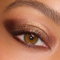 Bronze-gold metallic eyeshadow catches light on a close-up eye, blended into a deep brown smoky outer corner, showcasing the New Moon shadow palette, a ColourPop Shadow Palette, for warm neutral glam with defined lashes.