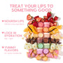Orange Vanilla Lip Mask jar anchors a vertical stack of pastel lip mask pots, surrounded by fresh strawberries, orange wedges, vanilla bean, cake, chocolate chunks, pistachio gelato, and jelly donut bites, highlighting the ColourPop Lip Care Kit in a bright flat lay.