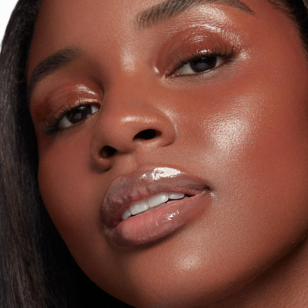 Glossy, plumped lips catch the light, showcasing Double The Juiciness from the ColourPop So Juicy Plumping Glossy Lip Oil & Lip Liner Kit; dewy skin and copper shimmer eyeshadow frame the close-up, highlighting a high-shine, cushiony finish.