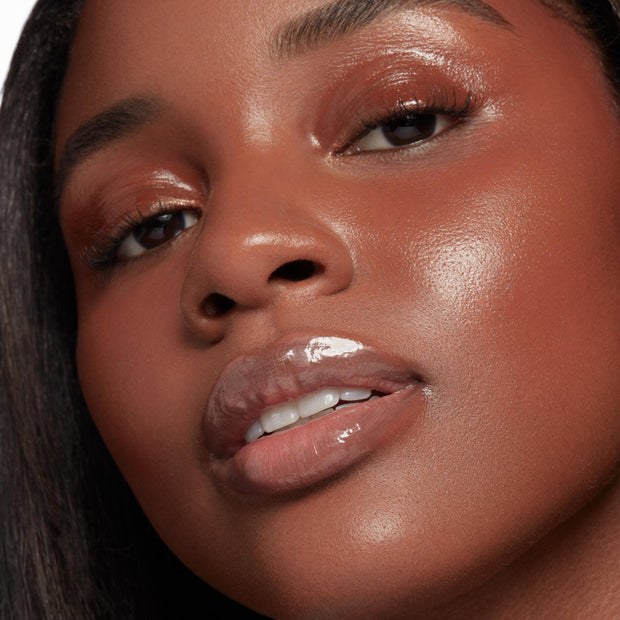 Glossy, plumped lips catch the light, showcasing Double The Juiciness from the ColourPop So Juicy Plumping Glossy Lip Oil & Lip Liner Kit; dewy skin and copper shimmer eyeshadow frame the close-up, highlighting a high-shine, cushiony finish.
