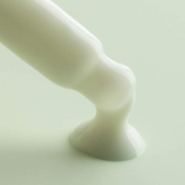 Matcha Face Milk flowing from an applicator tip and pooling into a glossy white puddle on a soft mint background, highlighting the creamy texture of ColourPop Face Milk skincare.