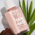 Later Hater Spot Treatment face treatment by Fourth Ray Beauty tilts on marble, a pink 1 fl oz (30 ml) bottle with white cap reflecting light, styled with tea tree leaves and volcanic rock, showcasing ColourPop skincare packaging.