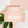 Peach-pink jar of The Daily Face Cream by Fourth Ray Beauty resting on glossy green leaves, flanked by white cream swipes on a blush background, highlighting this hydrating ColourPop Face Moisturizer for everyday use.