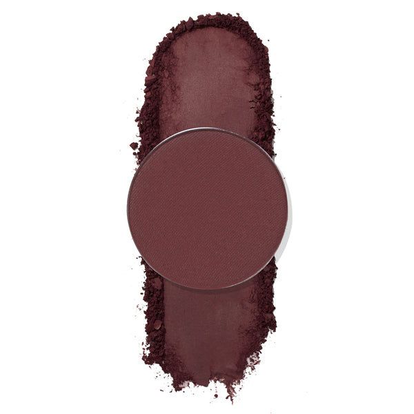 Facet pressed powder shadow by ColourPop, a round single pan in deep burgundy plum, shown with a vertical swatch and soft crumbled edges on a white background.