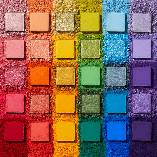 Fade Into Hue shadow palette displays 30 square pans in a rainbow grid - matte, shimmer, and pressed glitter - set on crushed pigment in a deconstructed flat lay; a vibrant ColourPop Shadow Palette.
