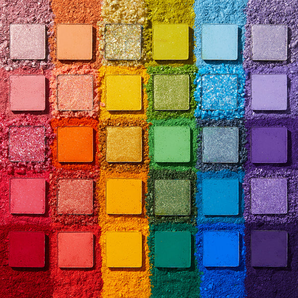 Fade Into Hue shadow palette displays 30 square pans in a rainbow grid - matte, shimmer, and pressed glitter - set on crushed pigment in a deconstructed flat lay; a vibrant ColourPop Shadow Palette.