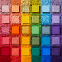 Fade Into Hue shadow palette displays 30 square pans in a rainbow grid - matte, shimmer, and pressed glitter - set on crushed pigment in a deconstructed flat lay; a vibrant ColourPop Shadow Palette.