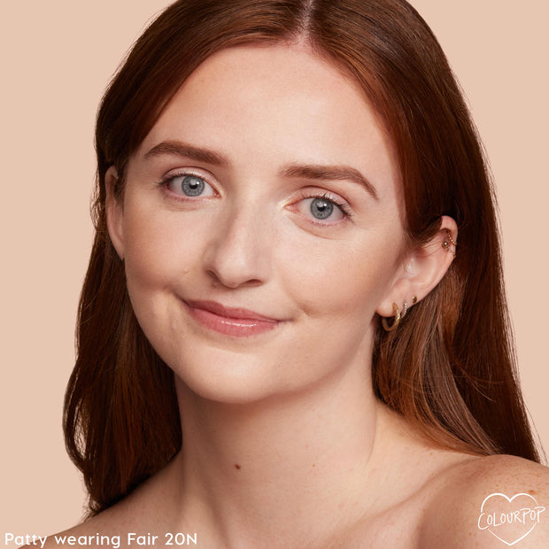 Model wearing ColourPop Hyaluronic Hydrating Foundation in Fair 20 N, showcasing smooth, even coverage with a natural, hydrated glow; close-up portrait on a peach-beige background highlighting shade match and skin finish.