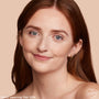 Model wearing ColourPop Hyaluronic Hydrating Foundation in Fair 20 N, showcasing smooth, even coverage with a natural, hydrated glow; close-up portrait on a peach-beige background highlighting shade match and skin finish.