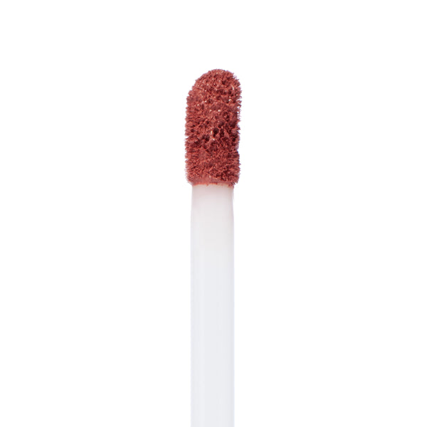 Doe-foot applicator coated in Fifth Avenue, a warm rosy nude liquid lipstick, gliding-ready on a white wand against a clean white background; ColourPop Ultra Matte Lip product shot, macro texture detail.