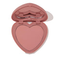 Heart-shaped dusty-rose compact opens halfway to reveal Flirt Alert, a soft rosy pink ColourPop Pressed Powder Blush in a heart pan with built-in mirror, shown on a clean white background.