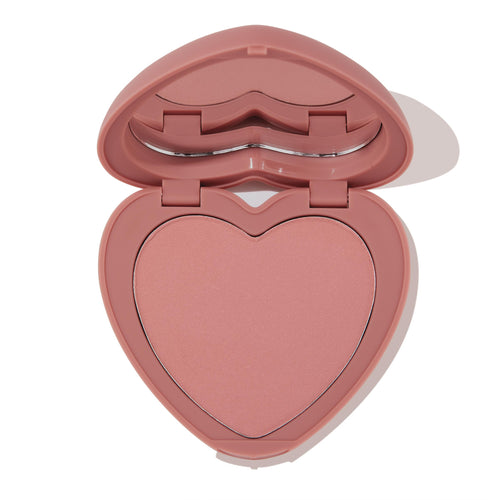 Heart-shaped dusty-rose compact opens halfway to reveal Flirt Alert, a soft rosy pink ColourPop Pressed Powder Blush in a heart pan with built-in mirror, shown on a clean white background.