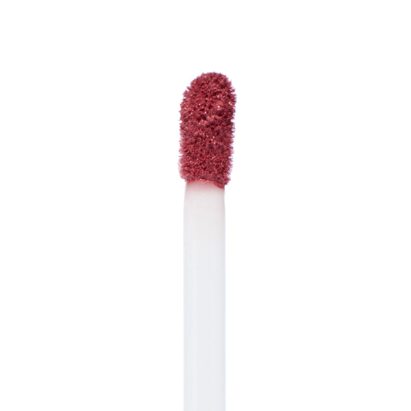 Doe-foot applicator coated in Flurries Ultra Matte Lip, a rosy mauve liquid lipstick, poised for precise application in a clean macro close-up on white; ColourPop makeup product detail.