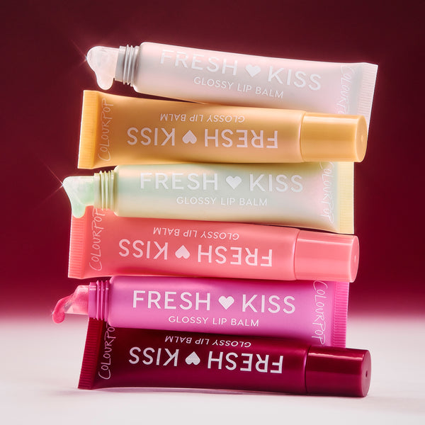 Colourpop Shine. Shimmer. Repeat. full collection set of Fresh Kiss glossy lip balms stacked in six pastel and bold tubes with pearly shimmer on applicators, beauty value set displayed against a pink gradient background.