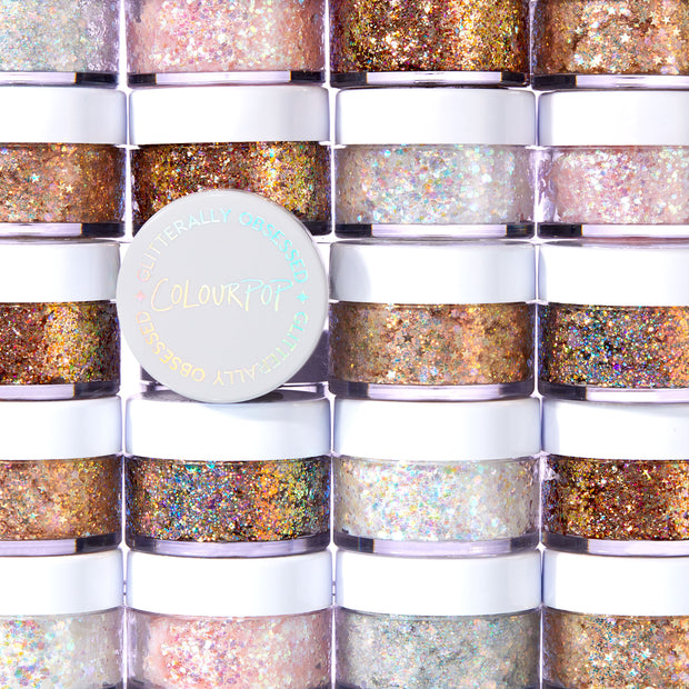 Ur A Firework ColourPop Glitter Gel jar shining with holographic sparkle, resting on stacked white-lidded pots, showcasing the Glitterally Obsessed collection in a bright studio setting with multicolor glitter visible through clear sides.