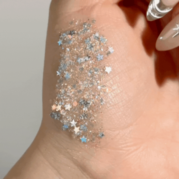 Ur A Firework ColourPop Glitter Gel swatched on the back of a hand, sparkling with chunky star and hex glitter in silver, blue, and iridescent hues suspended in clear gel, shown close-up to highlight texture and payoff.