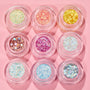 Nine Glitter Hour ColourPop Glitter Gel pots sparkle in a 3x3 grid, featuring iridescent white, icy blue, silver holo, mint, peach, yellow, rose gold with heart confetti, fuchsia, and opal mixes on a pastel pink background.