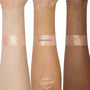 Floating Lights ColourPop Glitter Gel swatched in wide bands on three forearms, showing iridescent pink-lavender and gold multi-size glitter in a sheer gel base, demonstrating payoff across light, medium, and deep skin tones.
