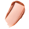 Glossy caramel nude balm swatch spreading in a smooth, high-shine swipe on white, showcasing ColourPop Fresh Kiss Glossy Balm in Caramel Latte, a sheer warm beige with a latte tint.