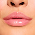 Glossy pink lips wearing Cherry Glaze, a ColourPop Fresh Kiss Glossy Balm, reflecting light with a glassy shine and sheer pink-cherry tint; extreme close-up highlights smooth, hydrated texture on natural lips.