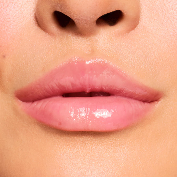 Glossy pink lips wearing Cherry Glaze, a ColourPop Fresh Kiss Glossy Balm, reflecting light with a glassy shine and sheer pink-cherry tint; extreme close-up highlights smooth, hydrated texture on natural lips.