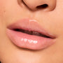 Lips wearing ColourPop Fresh Kiss Glossy Balm in Mango Sorbet, showing a high-shine, sheer peachy-pink tint and smooth, hydrated finish in a studio macro close-up.