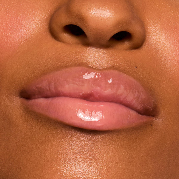 Glossy lips wearing Mango Sorbet, ColourPop Fresh Kiss Glossy Balm, with a high-shine, sheer peachy‑pink tint in a tight macro close-up, emphasizing smooth hydration and a plump, cushiony finish.