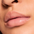 Glossy nude lips wearing ColourPop Fresh Kiss Glossy Balm in Vanilla Cake, captured in a tight macro close-up, showing a sheer pink-beige tint with high shine, smooth hydration, and a cushiony finish on natural skin.