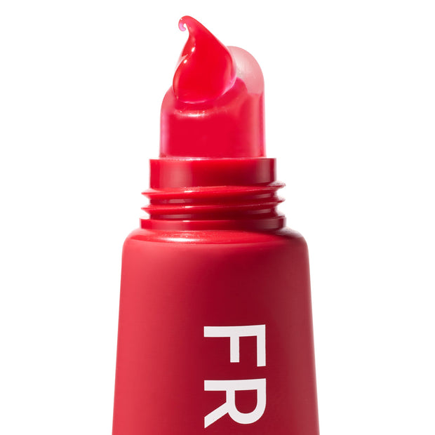 Cherry Glaze ColourPop Fresh Kiss Glossy Balm dispensing cherry-red gloss from an angled applicator tip, shown in a macro close-up of the squeeze tube with partial “FR” lettering against a clean white background.