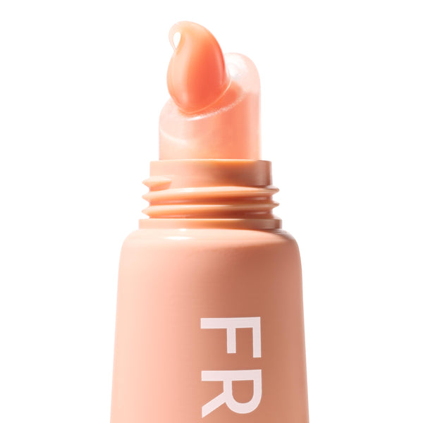 Squeeze‑tube lip balm applicator dispensing a glossy peach tint, shade Mango Sorbet, on a soft peach tube with partial “FR” lettering; ColourPop Fresh Kiss Glossy Balm shown in a crisp macro studio close‑up on white.