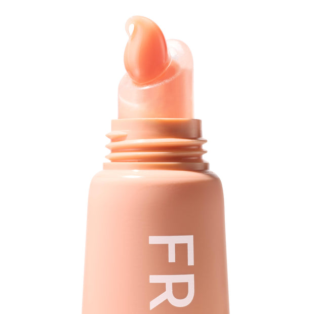 Squeeze‑tube lip balm applicator dispensing a glossy peach tint, shade Mango Sorbet, on a soft peach tube with partial “FR” lettering; ColourPop Fresh Kiss Glossy Balm shown in a crisp macro studio close‑up on white.