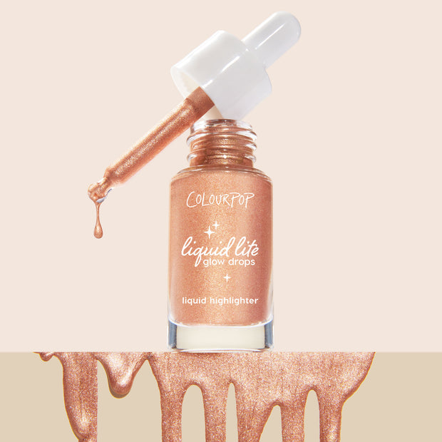 Venice Blvd ColourPop Liquid Highlighter shows an open glass bottle as a white-capped dropper drips shimmery rose-gold glow drops, the “liquid lite glow drops” label visible, with metallic swatches pooling along the bottom on a nude backdrop.