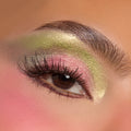 Shimmery chartreuse and rosy pink shadows blend across a close-up eyelid with fluttery lashes and a defined brow, showcasing the ColourPop How the Grinch Stole Christmas Shadow Palette holiday eye look.