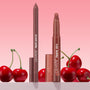 ColourPop Lippie Stix + Pencil Set Big Smooch stands uncapped, revealing a rosy brown lipstick and matching liner with caps nearby, styled among glossy cherries against a soft pink gradient backdrop.