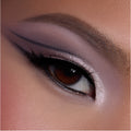 Close-up of a brown eye wearing shimmering mauve and pink shadow from the Heart to Get shadow palette, with sharp graphic black liner and highlighted inner corner, showcasing bold glam eye makeup detail.