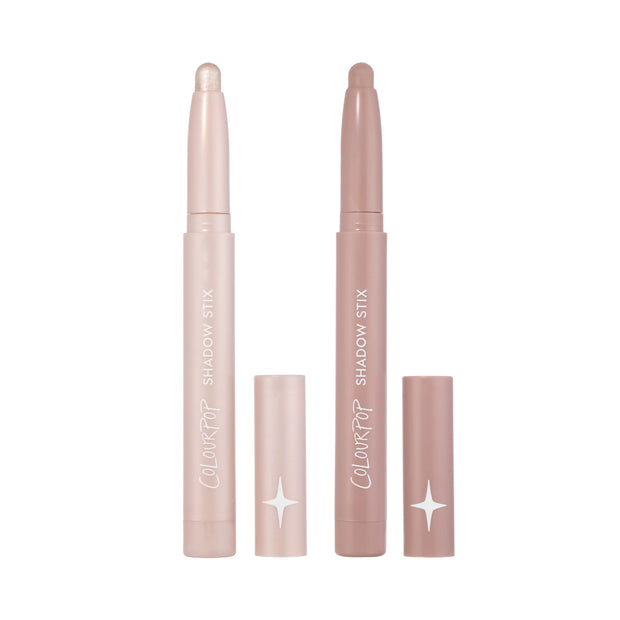 Two ColourPop Shadow Stix from the For Your Eyes Only Heart to Get kit stand upright with caps off, showing shimmery champagne and matte mauve cream eyeshadow sticks against a clean white background.