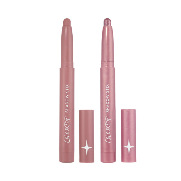 Two ColourPop Love At First Swipe Shadow Stix in the Heart to Get duo stand uncapped on a white background, showing matte mauve and shimmery pink cream eyeshadow sticks with matching pink tubes and star logo for easy swipe-on eye makeup.