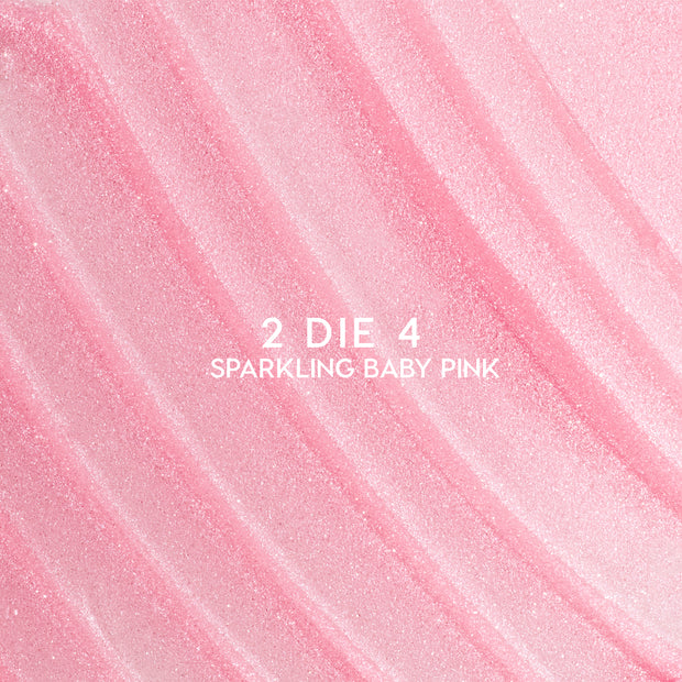 Heart to Get 2 Die 4 ultra glossy lip swatch showing sparkling baby pink shimmer in diagonal, textured streaks against a smooth pastel background, highlighting the high-shine, glittery finish for US makeup lovers.