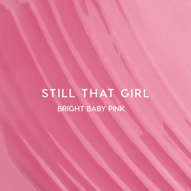 Still That Girl Ultra Glossy Lip Heart to Get swatch showing smooth, bright baby pink lip gloss spread in soft ridges across a solid pink background, highlighting its high-shine, creamy texture for bold, glossy lips.