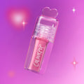ColourPop Your New Obsession ultra glossy lip in the Heart to Get shade floats diagonally against a glowing pink and purple background, clear tube and heart-shaped cap highlighting the high-shine pink gloss for a dreamy makeup look.