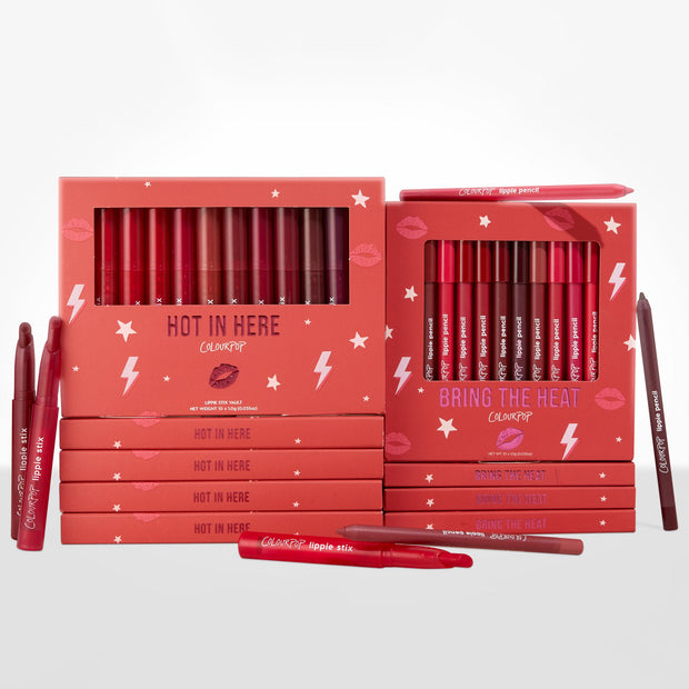 Heat Warning ColourPop Lippie Vault Set displays two coral boxes - Hot In Here Lippie Stix and Bring The Heat Lippie Pencil - showcasing red, berry, and nude shades, with extra sticks and pencils scattered on a white studio surface.