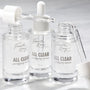 Fourth Ray Beauty All Clear Purifying Serum, a ColourPop Face Serum, three clear 0.85 fl oz (25 mL) glass dropper bottles with pipettes releasing transparent drops on a bright white surface.