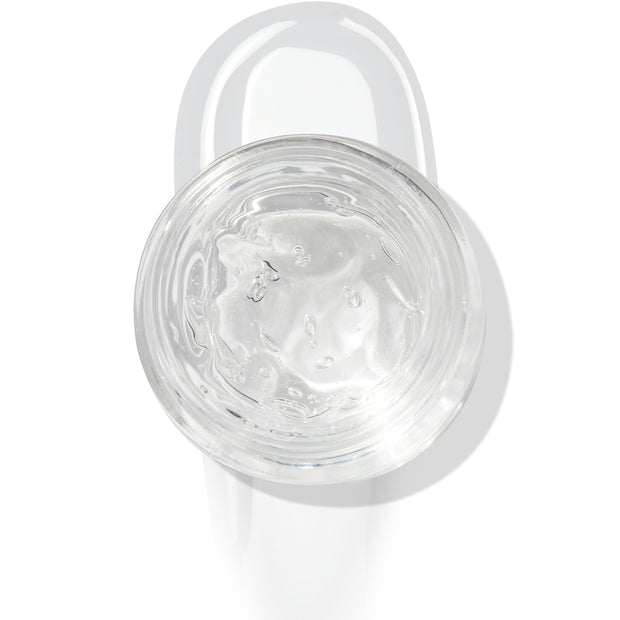 In The Clear Face & Eye Gloss in an open round jar gleams with a glossy swipe beneath it on a white background, showcasing the ColourPop Face & Eye Gloss for dewy, glass-skin shine on lids and cheeks.