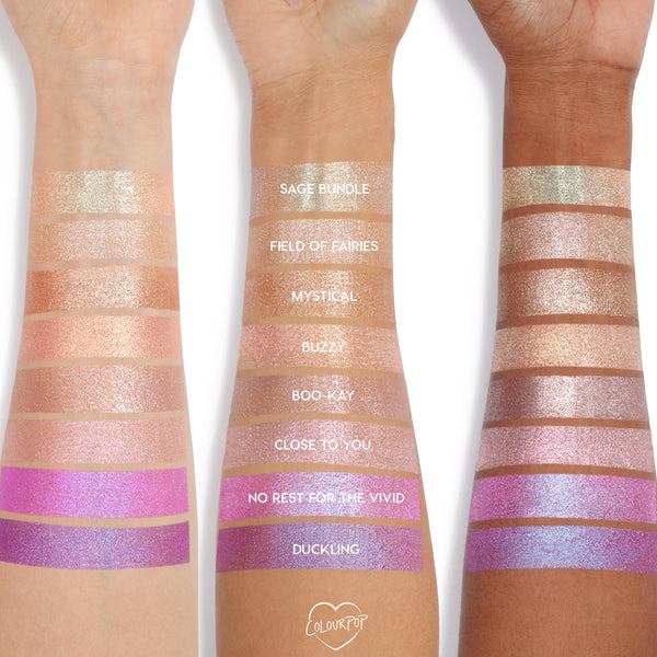 Three forearms with different skin tones display swatches of Colourpop Hallucinogenius Jelly Much Shadow eyeshadow shades, from champagne neutrals to vivid iridescent pinks and purples, showing shimmer payoff and color range.