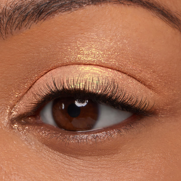 ColourPop Jelly Much Shadow in Buzzy shimmering across a brown eyelid, reflecting peachy-gold metallic glow, shown in a macro close-up with natural lashes under studio lighting.