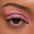 Rosy pink eyelid wearing ColourPop Jelly Much Shadow in Close To You, shimmering in an even metallic wash across the lid and softly blended into the crease, accenting a brown eye with natural lashes and a groomed brow in a studio close-up.