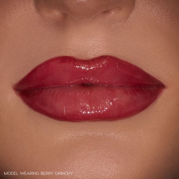 Glossy berry-stained lips wearing ColourPop Berry Grinchy So Juicy Plumping Gloss Stick, delivering plumped shine and a sheer berry tint in a tight close-up against natural skin.